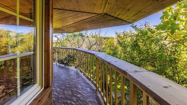 A wooden deck with a glass balustrade overlooking a garden. - Ferma Gold | Double Room by PikHost (Tiranë)