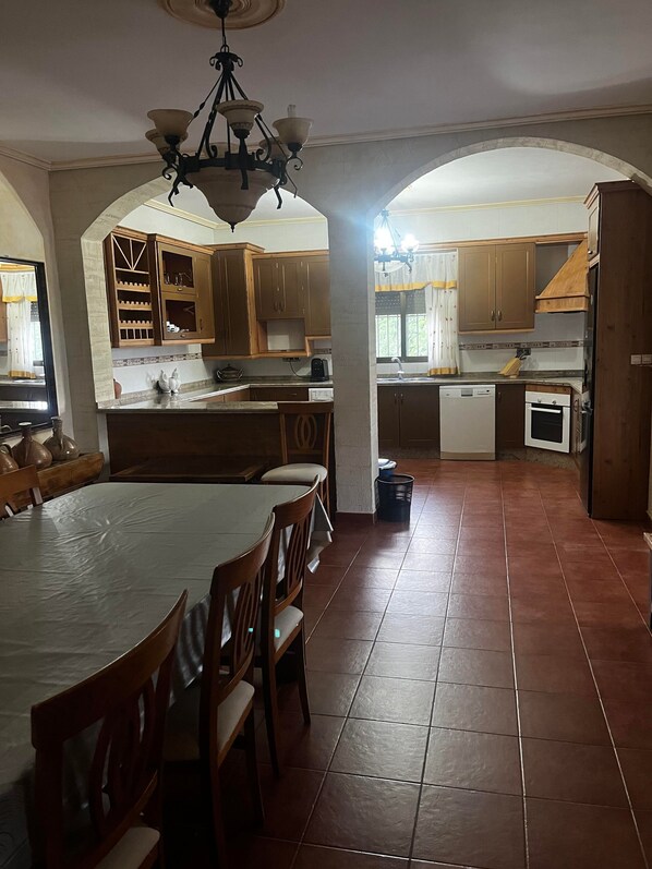 A spacious kitchen with an island, wooden cabinets, and a dining area with chairs.