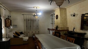Une chambre d’hôtel équipée d’une table à manger, de chaises, d’un canapé, d’un lit, d’un ventilateur de plafond, d’un lustre et d’une cheminée.