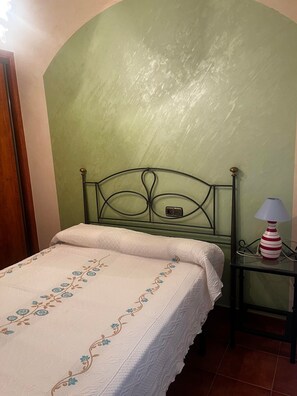 Une chambre à coucher avec un lit, une table de chevet et une lampe.