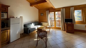 Een knus woongedeelte met een kitchenette, een bank, een eettafel en een televisie.