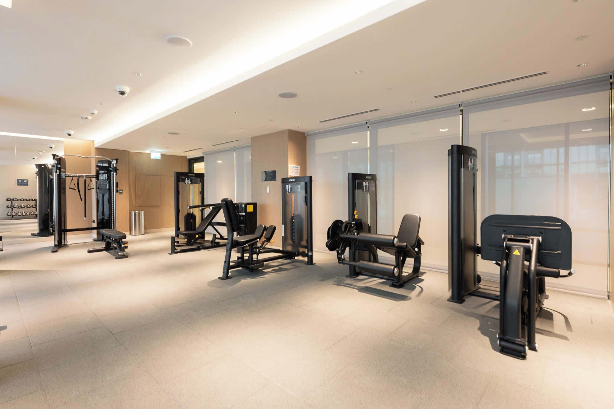 Une salle de sport moderne équipée de divers appareils d’exercice, d’un banc et d’haltères.