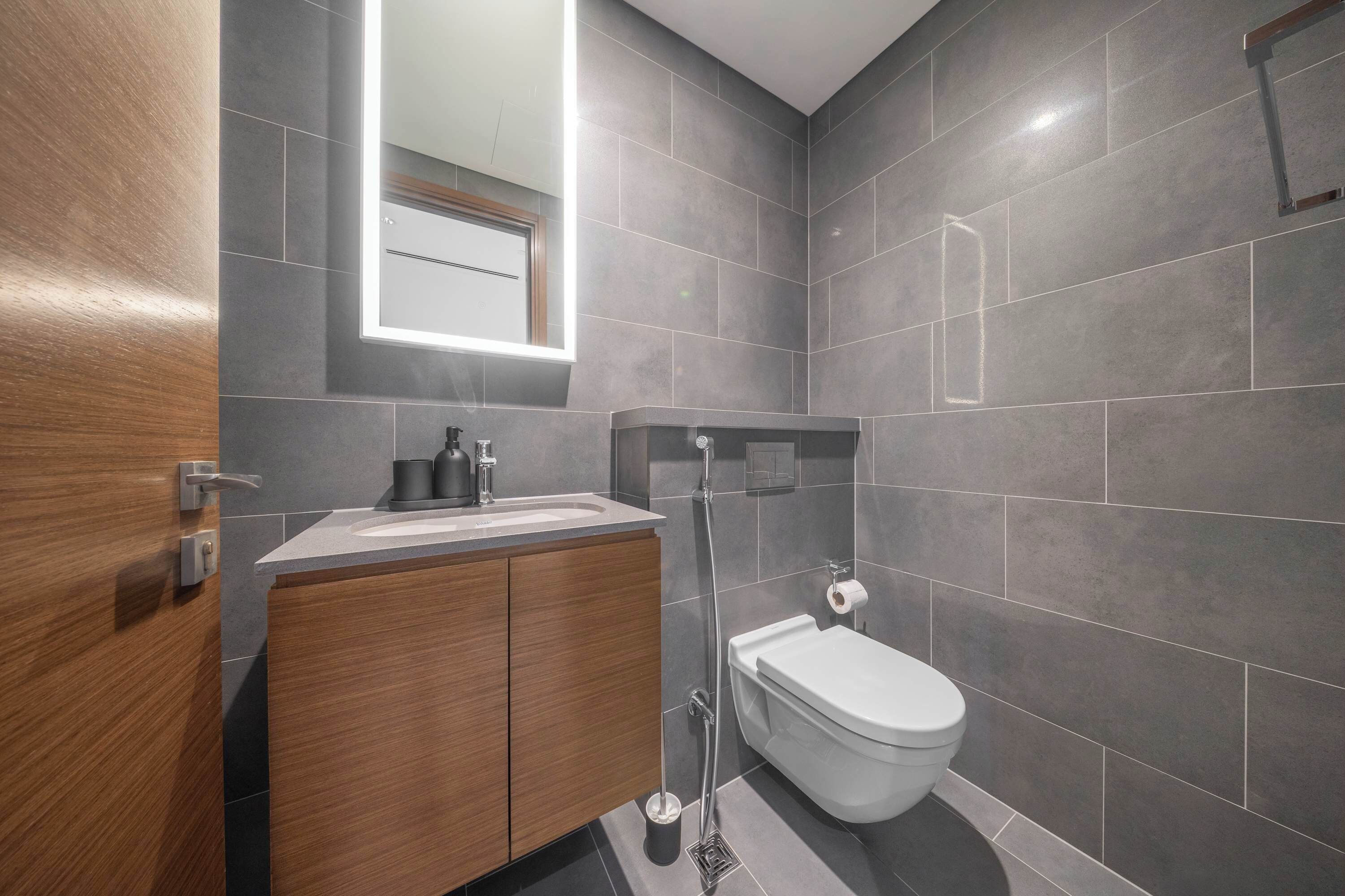 Une salle de bain moderne avec un meuble-lavabo en bois, des toilettes blanches et un miroir au-dessus du lavabo.
