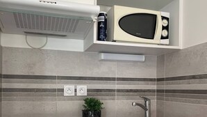 Een kleine keuken met een magnetron, een spoelbakje en een compacte koelkast.