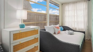 Una camera da letto con un letto, un comodino con una lampada e una finestra vista cielo.