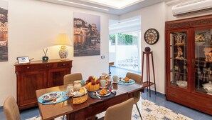 A dining area with a table set for breakfast, a wooden cabinet, and a decorative cabinet with glass doors. - Artist Lights in Luxury Apartment in the Center with A/C, WiFi, Outdoor Space (Salerno)