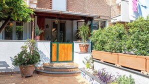 A courtyard with a wooden door, potted plants, and a tiled patio. - Artist Lights in Luxury Apartment in the Center with A/C, WiFi, Outdoor Space (Salerno)