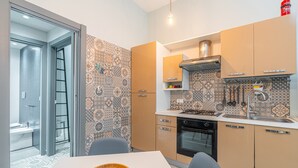 A modern kitchen with patterned backsplash, a stove, oven, and a dining area with a table and chairs. - Blue House Ground Floor Apartment with Wi-Fi and Air Conditioning (Portopalo di Capo Passero)