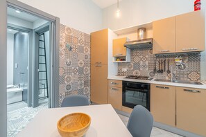 A modern kitchen with patterned backsplash, a stove, oven, and a dining area with a table and chairs.