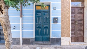 A building with a blue facade, a dark blue door, and a brown door. - Blue House Ground Floor Apartment with Wi-Fi and Air Conditioning (Portopalo di Capo Passero)