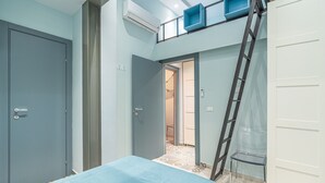 A room with a bed, a door, a ladder, and a small table. - Blue House Ground Floor Apartment with Wi-Fi and Air Conditioning (Portopalo di Capo Passero)