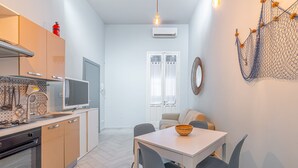 A modern kitchen with a dining area, white walls, and a hanging light fixture. - Blue House Ground Floor Apartment with Wi-Fi and Air Conditioning (Portopalo di Capo Passero)