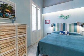 A bedroom with a bed, a wardrobe, a painting, and a wall-mounted light fixture. - Blue House Apartment with Terrace, Sea View, Wi-Fi and Air Conditioning (Portopalo di Capo Passero)