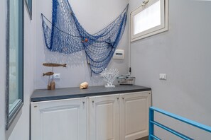 Een keuken met witte kasten, een blauw aanrecht en een blauwe decoratieve net.