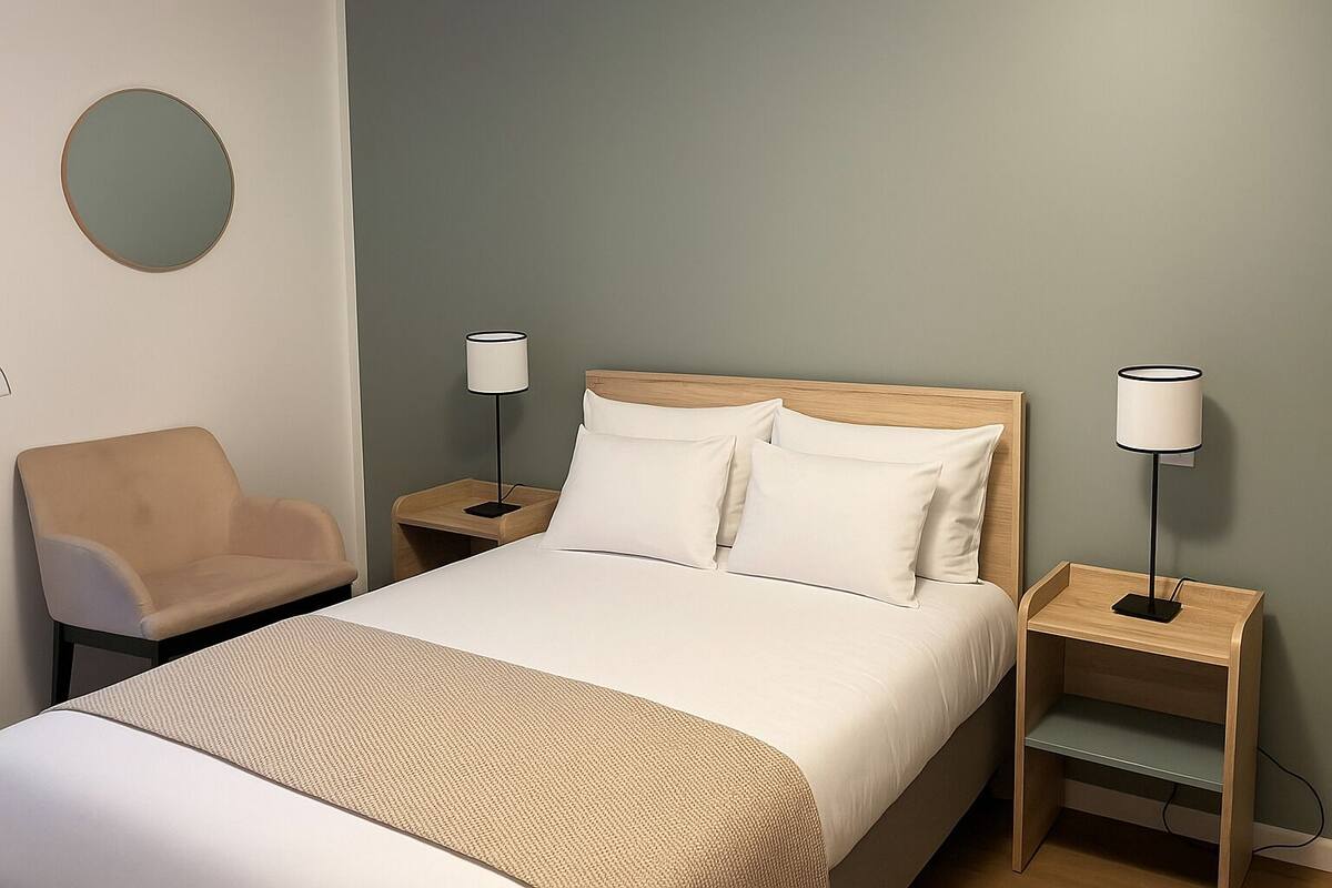 Een hotelkamer met een bed, twee nachtkastjes, een stoel en twee lampen.