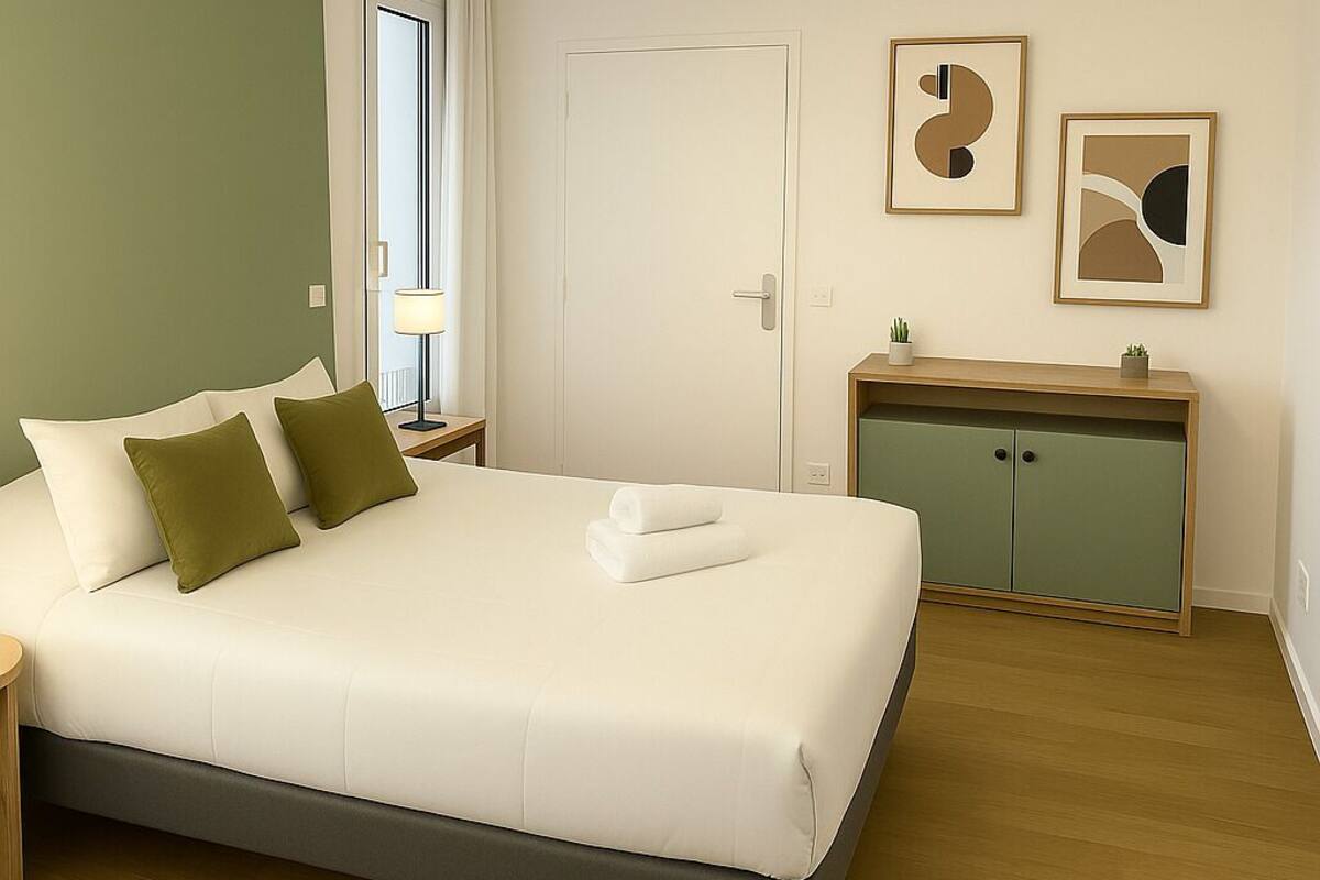 Een netjes ingerichte slaapkamer met een groot bed, nachtkastje, bureau en kast.