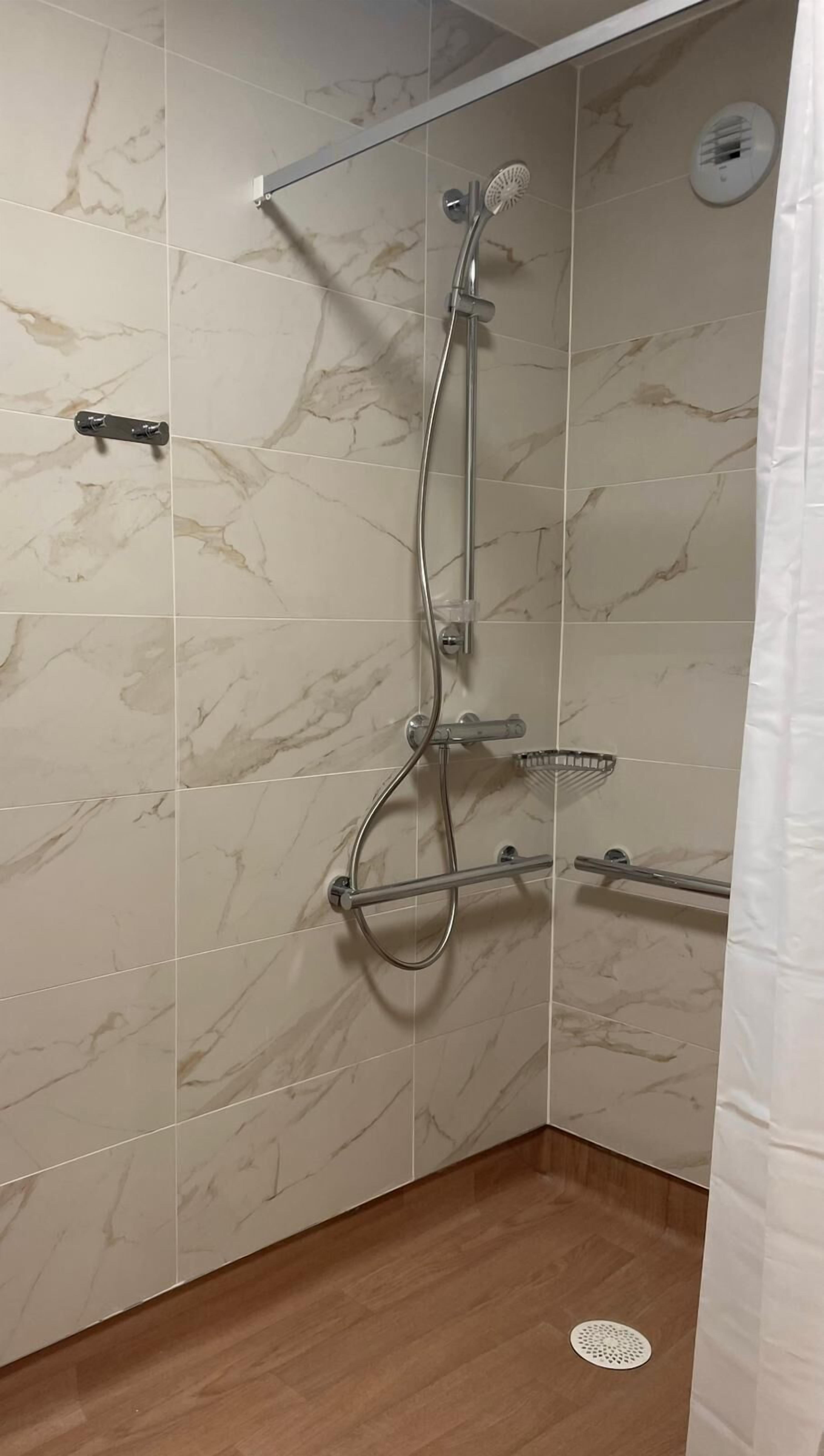 Une douche équipée d’un pommeau de douche à main, d’un robinet mural et d’un pommeau de douche à main.