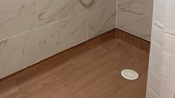 Une douche équipée d’un pommeau de douche à main, d’un robinet mural et d’un pommeau de douche à main.