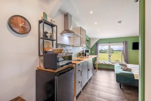 Une cuisine compacte dotée d’appareils électroménagers modernes, un coin repas avec vue et une chambre confortable avec un lit et une fenêtre.