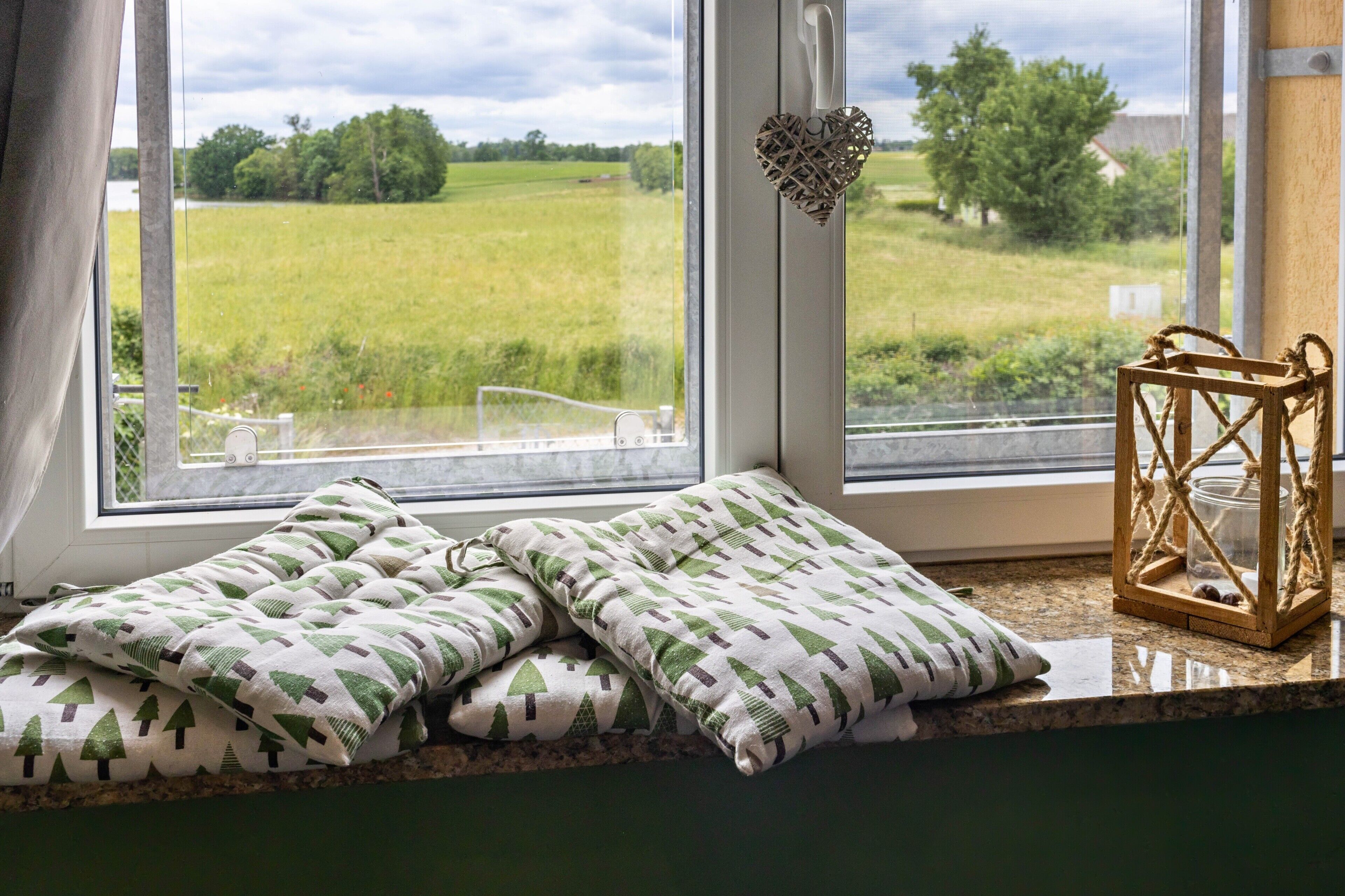 A window seat with cushions, a heart-shaped decoration, and a lantern.