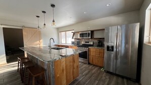 Una cocina moderna con una isla central, electrodomésticos de acero inoxidable y armarios de madera.