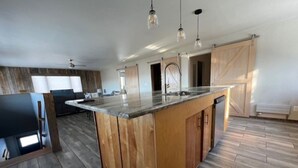 Una cocina amplia con una isla grande, armarios de madera e iluminación colgante.