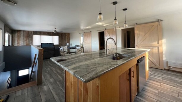 Una cocina amplia con una isla grande, armarios de madera e iluminación colgante.