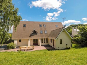A two-story house with a sloped roof, a small attached garage, and a paved driveway. - Lady Of Lourdes (Ross-on-Wye)