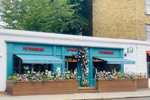Un escaparate con el nombre "PETROSSIAN" y letreros que indican "CAVIAR + PESCADO AHUMADO + TRUFAS" y "VINOS FINOS + CAFÉ GOURMET".