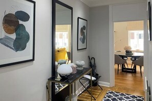A modern living room with a black console table, a large mirror, and abstract art on the wall. - Charming South Kensington One-Bedroom Near Harrods & Chelsea (London)