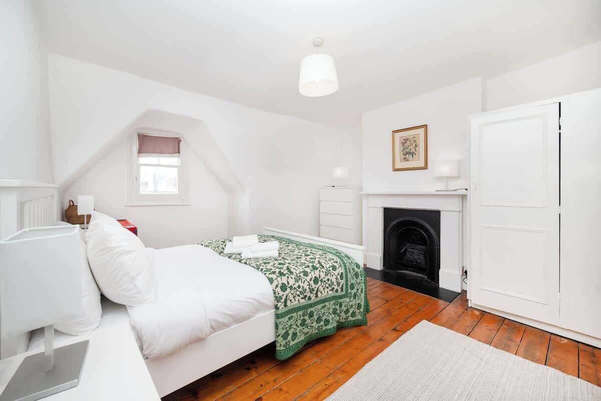 A bedroom with a bed, a fireplace, a wardrobe, and a window.