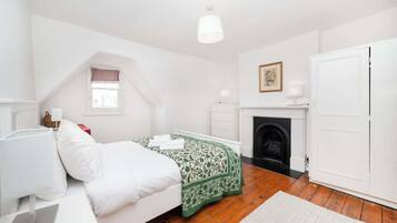 A bedroom with a bed, a fireplace, a wardrobe, and a window.