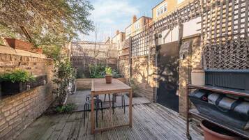 A patio with a table and chairs, surrounded by brick walls and a wooden fence.