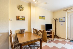 Ein Essbereich mit Holztisch und -stühlen, einem Fernseher auf einem Holzschrank und Wandbildern.