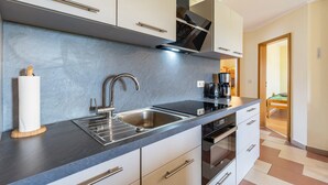 A modern kitchen with a stainless steel sink, a coffee maker, and a built-in oven.