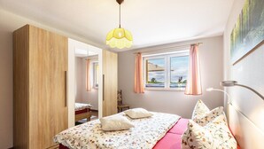 Une chambre à coucher avec un lit, une armoire, une fenêtre avec des rideaux et un tableau accroché au mur.