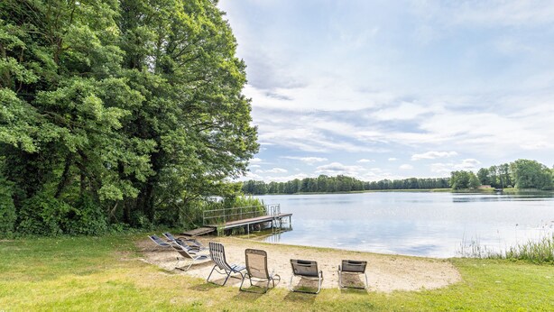 Une zone au bord du lac, avec un quai, des chaises longues et une pelouse.