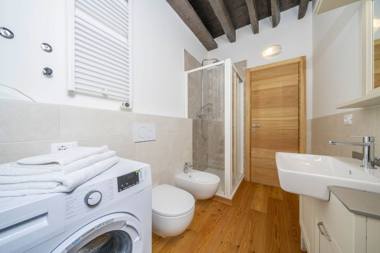 A modern bathroom with a washing machine, toilet, bidet, and shower.