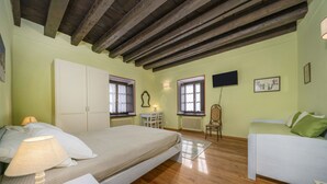 A room with a bed, a desk, a chair, a radiator, and a television. - GuestHost - A welcoming apartment of approximately 50 square meters, perfect for five people, located on the first floor of a historic building built in 1864 and renovated in 2025 while maintaining its historic atmosphere (NO elevator).The property is lo (Tarvisio)