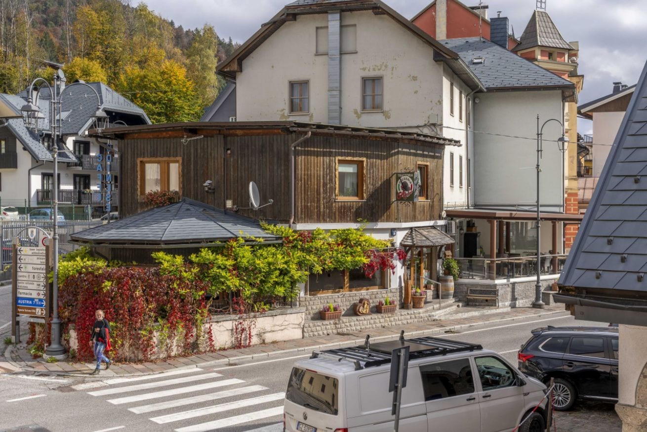 Un bâtiment de style architectural traditionnel, un passage piéton et une rue où circulent des véhicules.