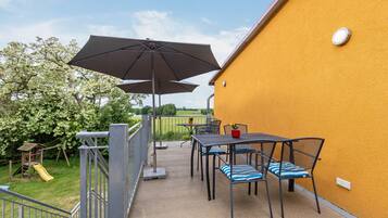 A patio with outdoor furniture, a play structure, and a yellow wall.