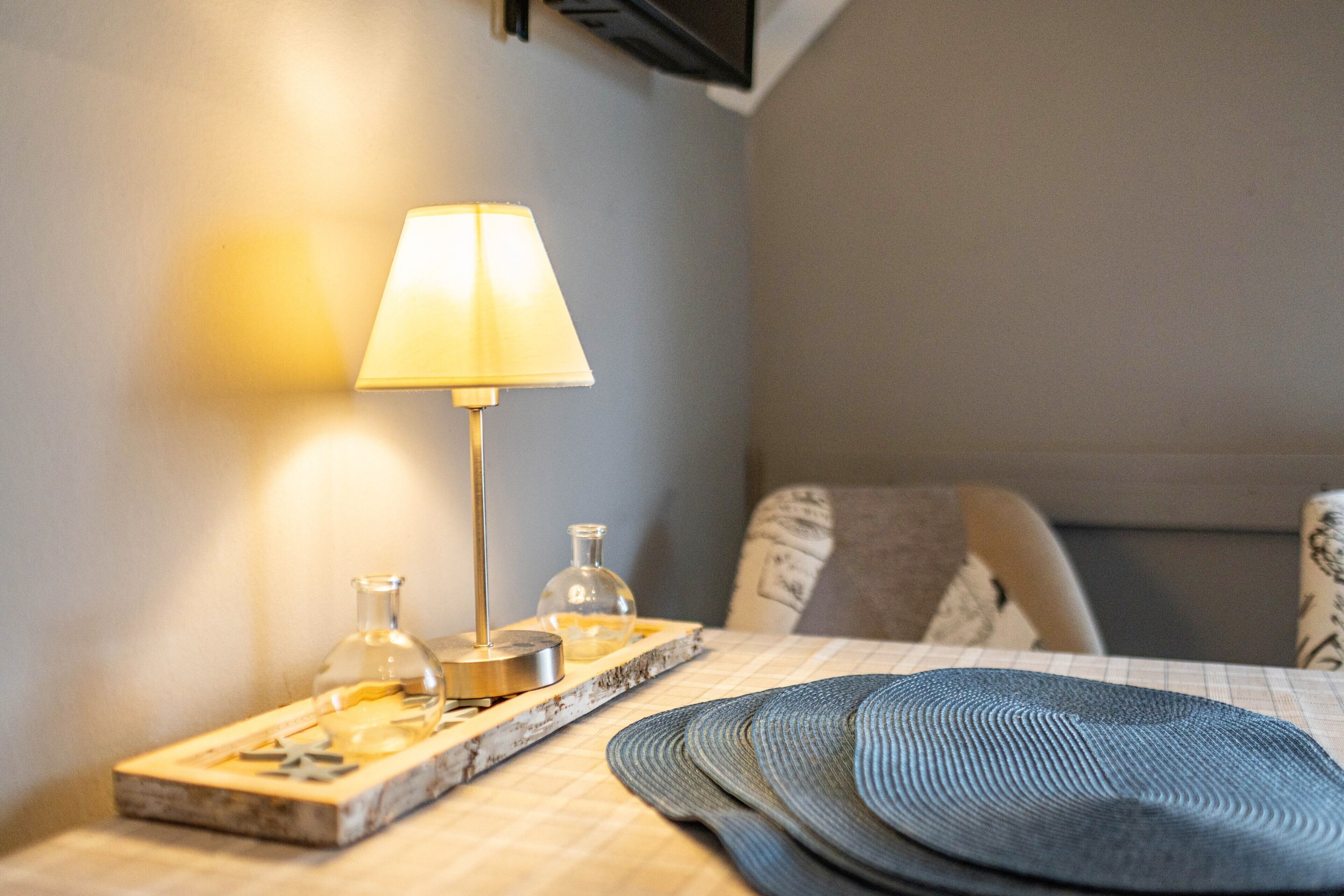 Une table bien rangée, avec une lampe, une bouteille en verre et un plateau.