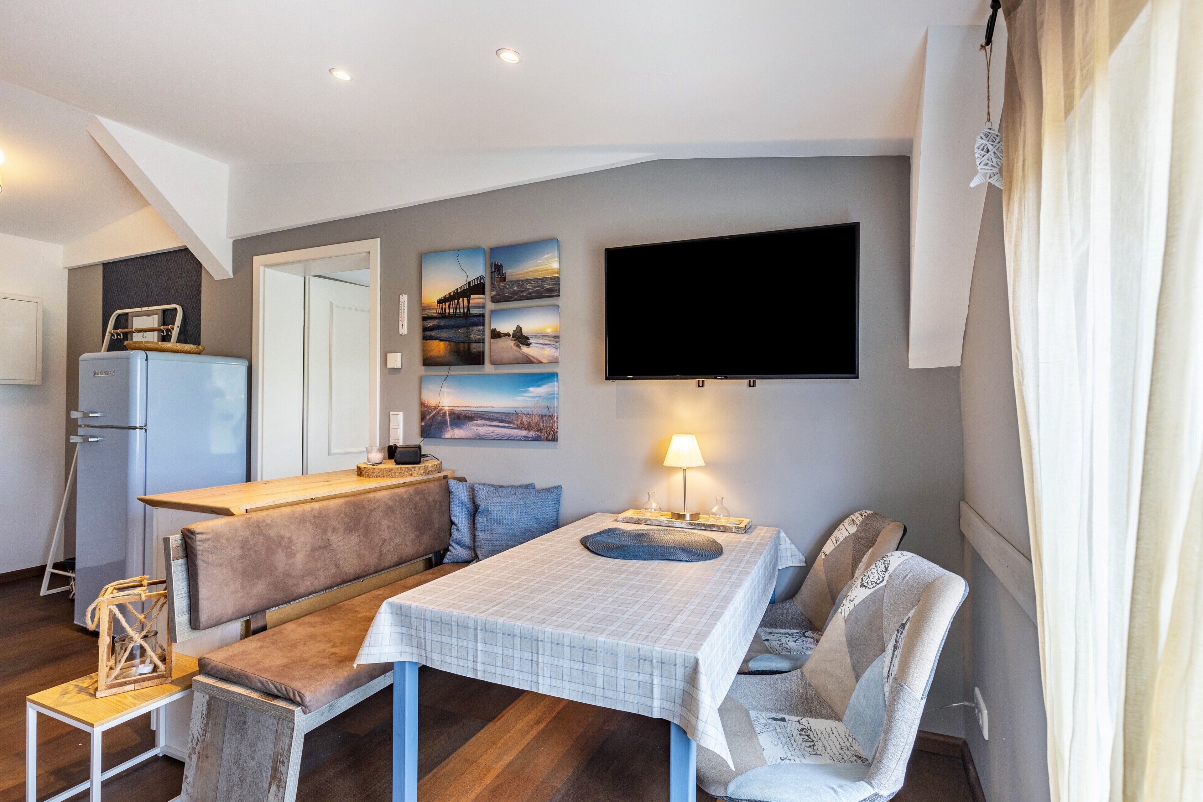 Et moderne værelse med sofa, bord, fjernsyn og bænk.
