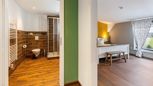 Un baño moderno con ducha, inodoro y un banco.