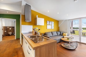 Une cuisine moderne équipée d’un évier, un coin repas avec une table ronde, un canapé et un balcon avec vue.