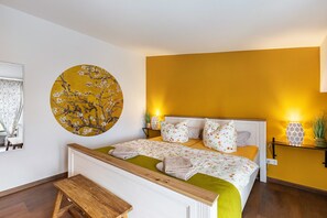 Une chambre à coucher comprenant un lit, une décoration murale ronde, une table de chevet, une commode et un banc.