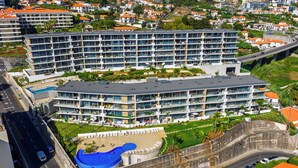 Un hotel moderno con diversi piani, una piscina sul tetto e un cortile curato.