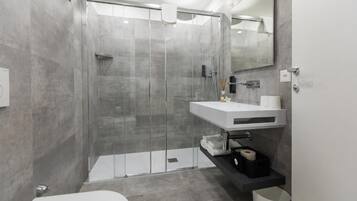 Ein modernes Badezimmer mit einer gläsernen Duschkabine, einem weißen Waschbecken und einer Toilette.