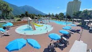 Ein Poolbereich mit mehreren Wasserrutschen, Liegestühlen und Sonnenschirmen.