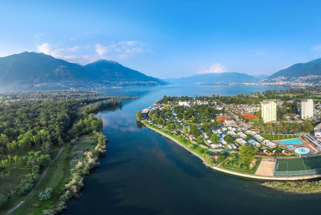 Vista aérea de un pueblo costero con un río, zonas residenciales y un complejo de edificios grande con piscina.